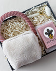 pink themed self care gift set includes an unwind kit in plush pouch, pink velvet headband, white and gold facial roller, pink cactus bar soap and concrete soap dish in a black keepsake box.
